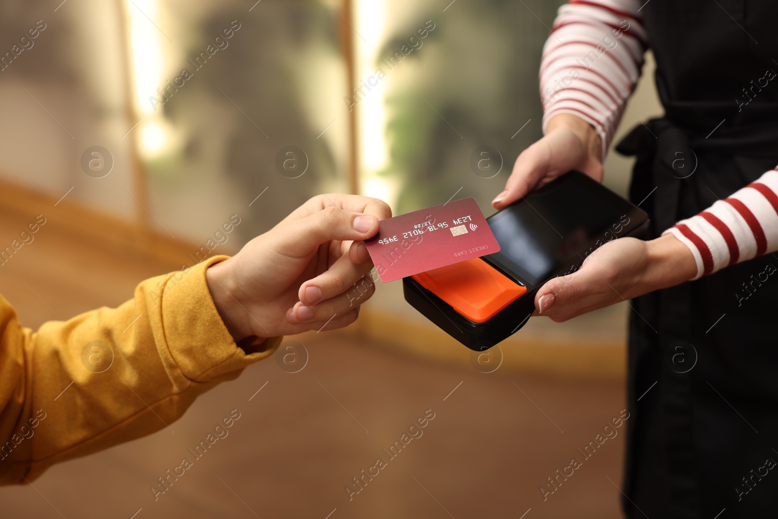 Photo of Man paying with credit card via terminal in cafe, closeup