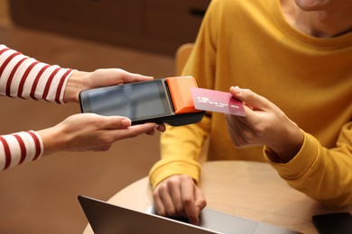 Photo of Man paying with credit card via terminal in cafe, closeup