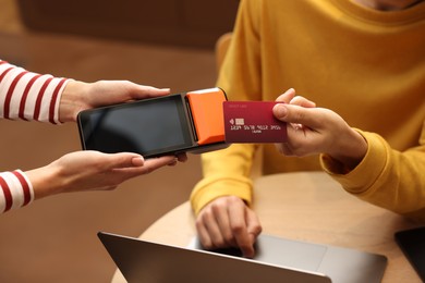 Photo of Man paying with credit card via terminal in cafe, closeup