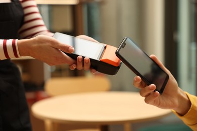 Photo of Man paying with smartphone via terminal in cafe, closeup