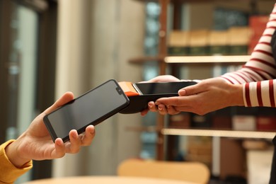 Photo of Man paying with smartphone via terminal in cafe, closeup