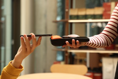 Photo of Man paying with smartphone via terminal in cafe, closeup