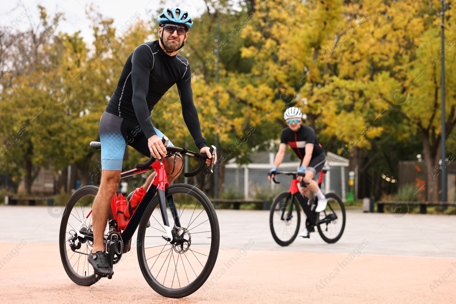 Photo of Athletic men with helmets riding bicycles outdoors