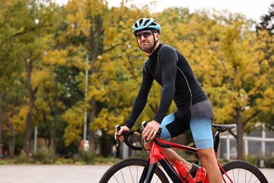 Photo of Athletic man with helmet riding bicycle outdoors