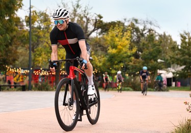 Photo of Group of athletic people riding bicycles outdoors, space for text