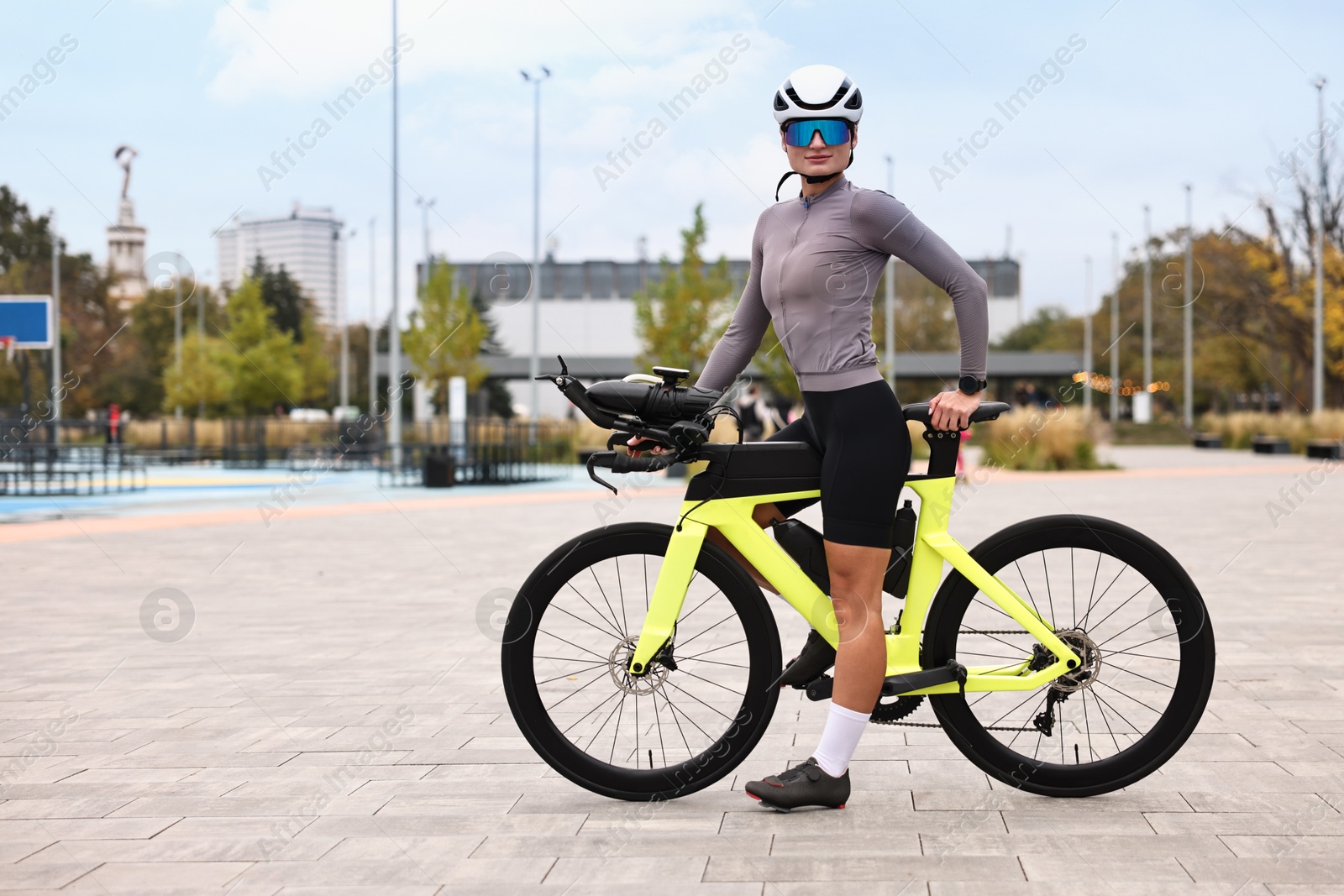 Photo of Young athletic woman with helmet and bicycle outdoors, space for text