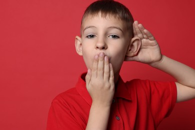 Photo of Little boy showing hand to ear gesture on red background