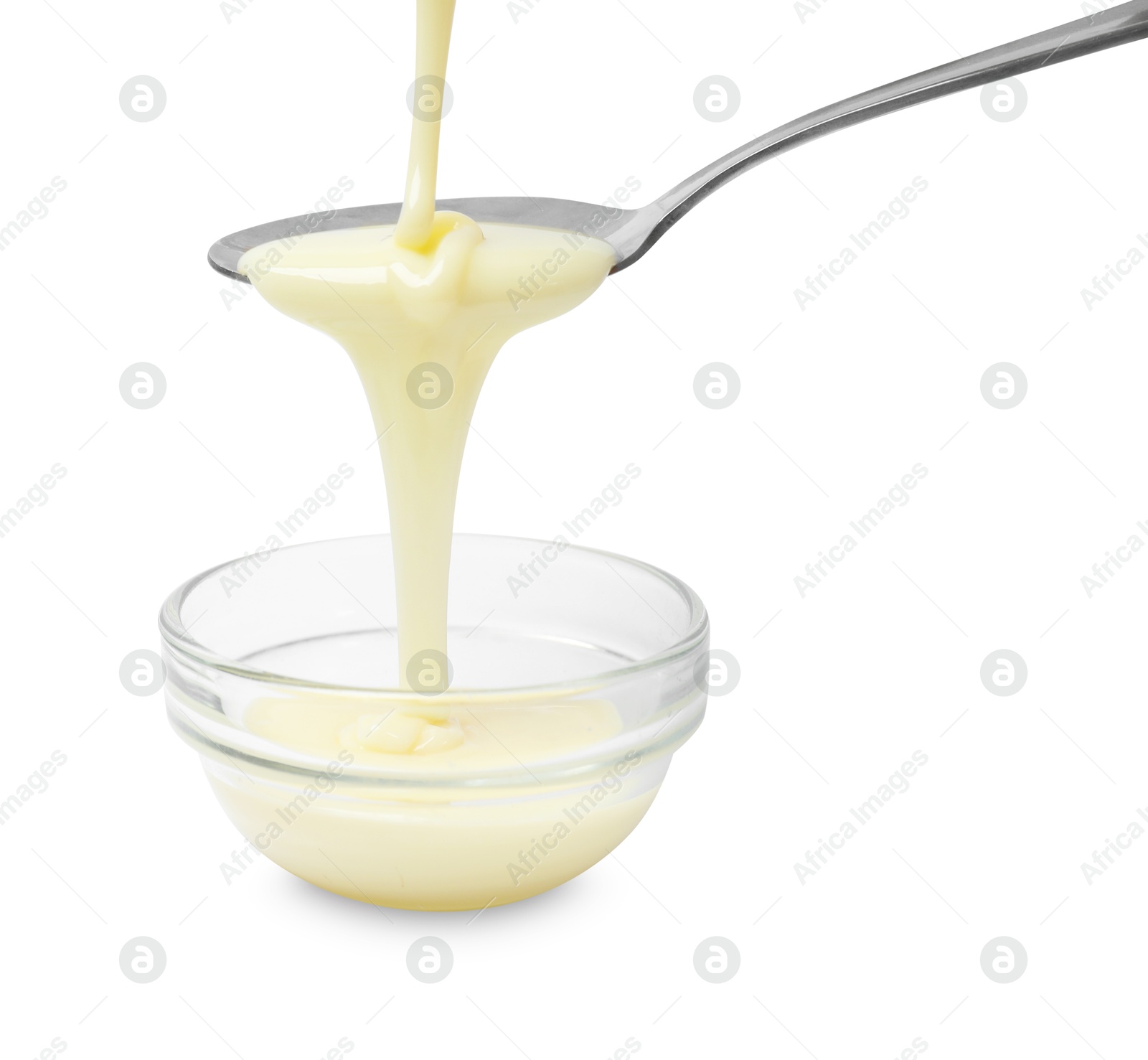 Photo of Condensed milk flowing down from spoon into bowl isolated on white