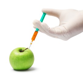 Photo of GMO concept. Scientist injecting something into green apple against white background, closeup