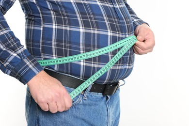 Photo of Overweight man measuring his belly with tape on white background, closeup