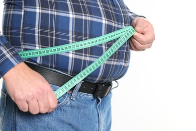 Photo of Overweight man measuring his belly with tape on white background, closeup