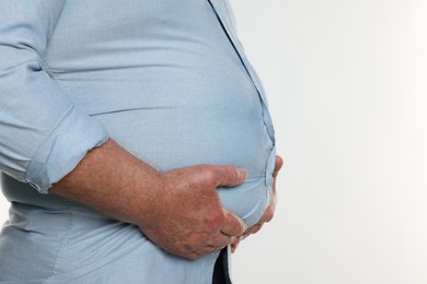 Photo of Overweight man in tight shirt on white background, closeup. Space for text