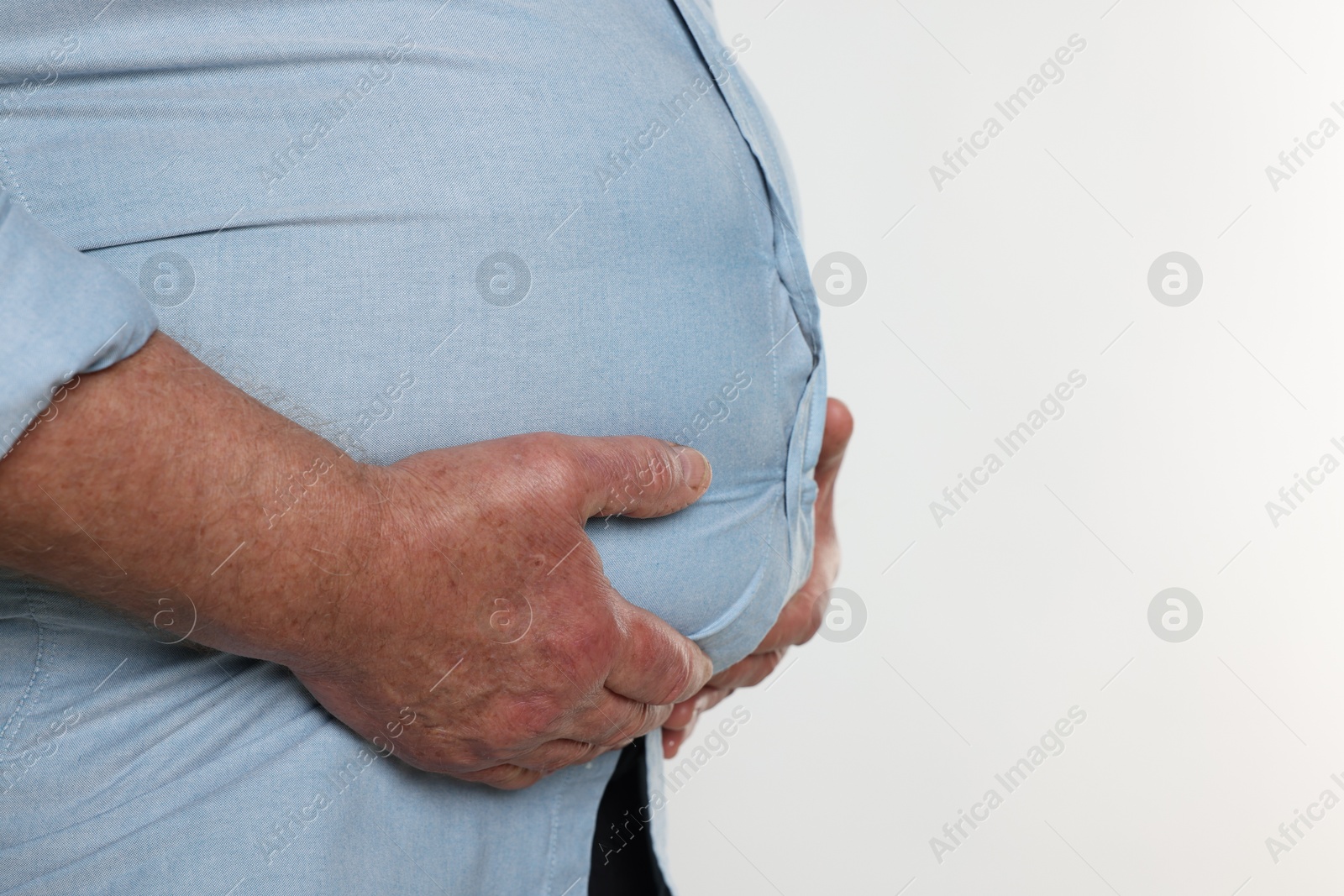 Photo of Overweight man in tight shirt on white background, closeup. Space for text