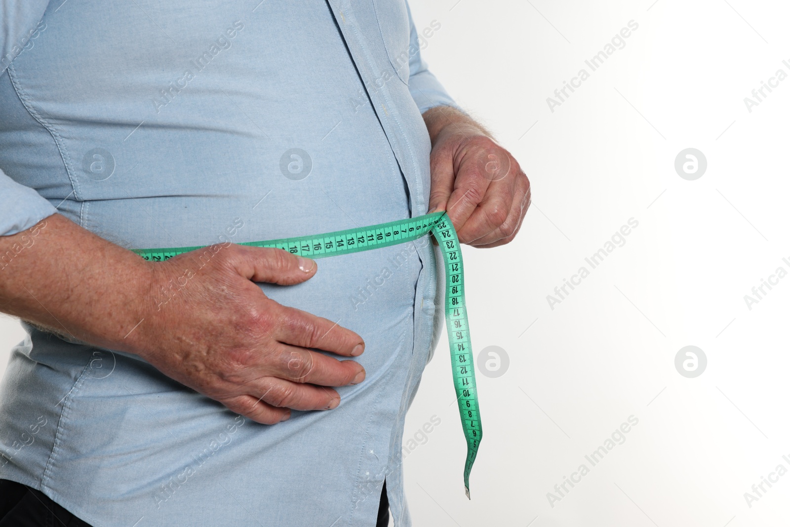 Photo of Overweight man measuring his belly with tape on white background, closeup. Space for text