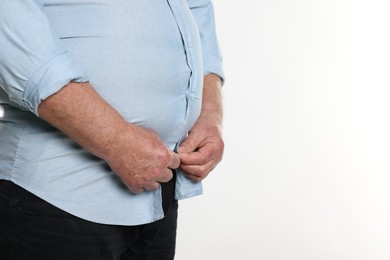 Photo of Overweight man trying to button up tight shirt on white background, closeup. Space for text