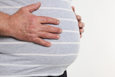 Photo of Overweight man in tight t-shirt on white background, closeup. Space for text