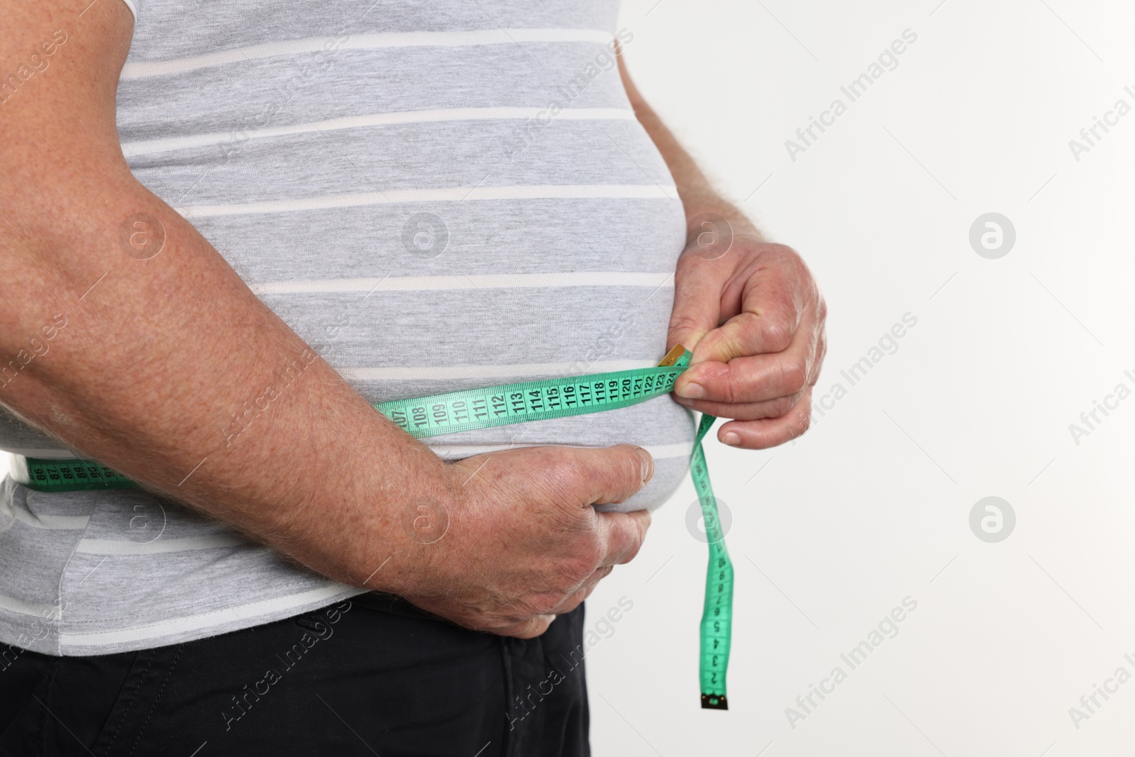 Photo of Overweight man measuring his belly with tape on white background, closeup. Space for text