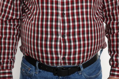 Photo of Overweight man in tight shirt on white background, closeup