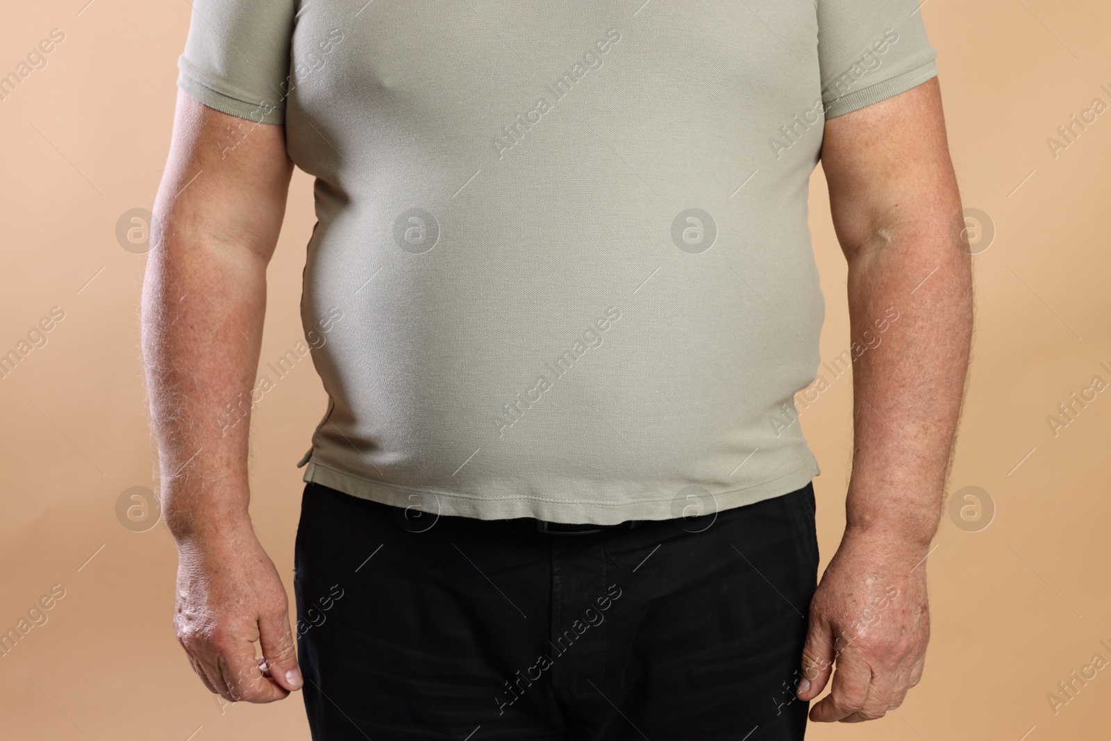 Photo of Overweight man in tight t-shirt on beige background, closeup