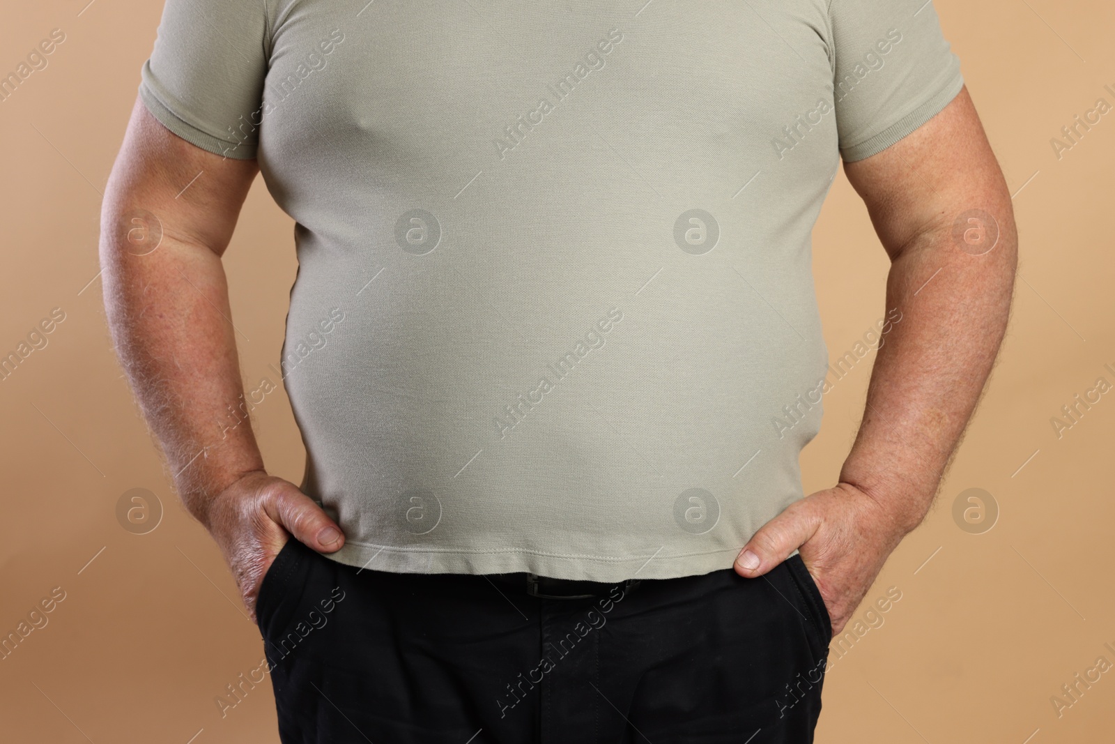 Photo of Overweight man in tight t-shirt on beige background, closeup