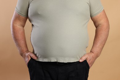 Photo of Overweight man in tight t-shirt on beige background, closeup