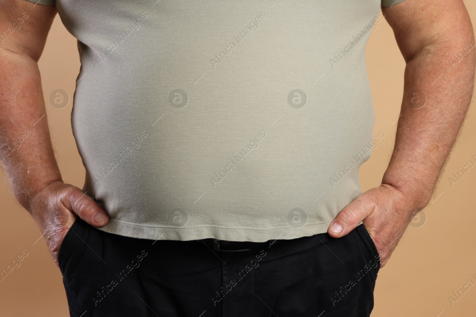 Photo of Overweight man in tight t-shirt on beige background, closeup