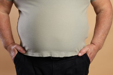 Photo of Overweight man in tight t-shirt on beige background, closeup