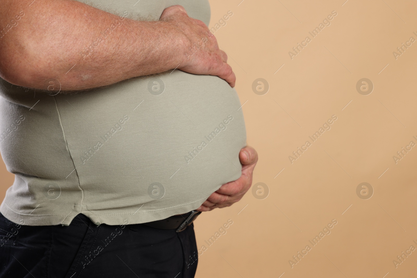 Photo of Overweight man in tight t-shirt on beige background, closeup. Space for text