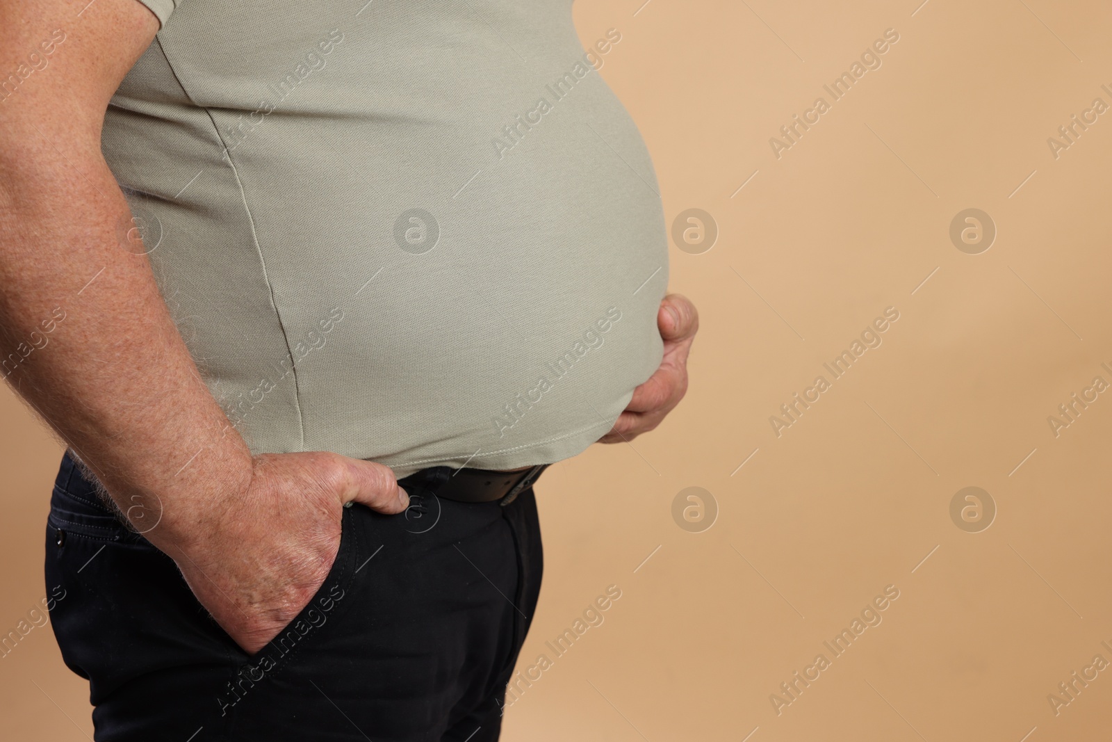 Photo of Overweight man in tight t-shirt on beige background, closeup. Space for text