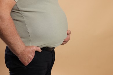 Photo of Overweight man in tight t-shirt on beige background, closeup. Space for text