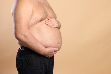 Photo of Overweight problem. Man with excessive belly fat on beige background, closeup. Space for text