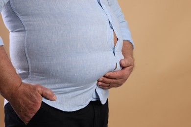 Photo of Overweight man in tight shirt on beige background, closeup. Space for text