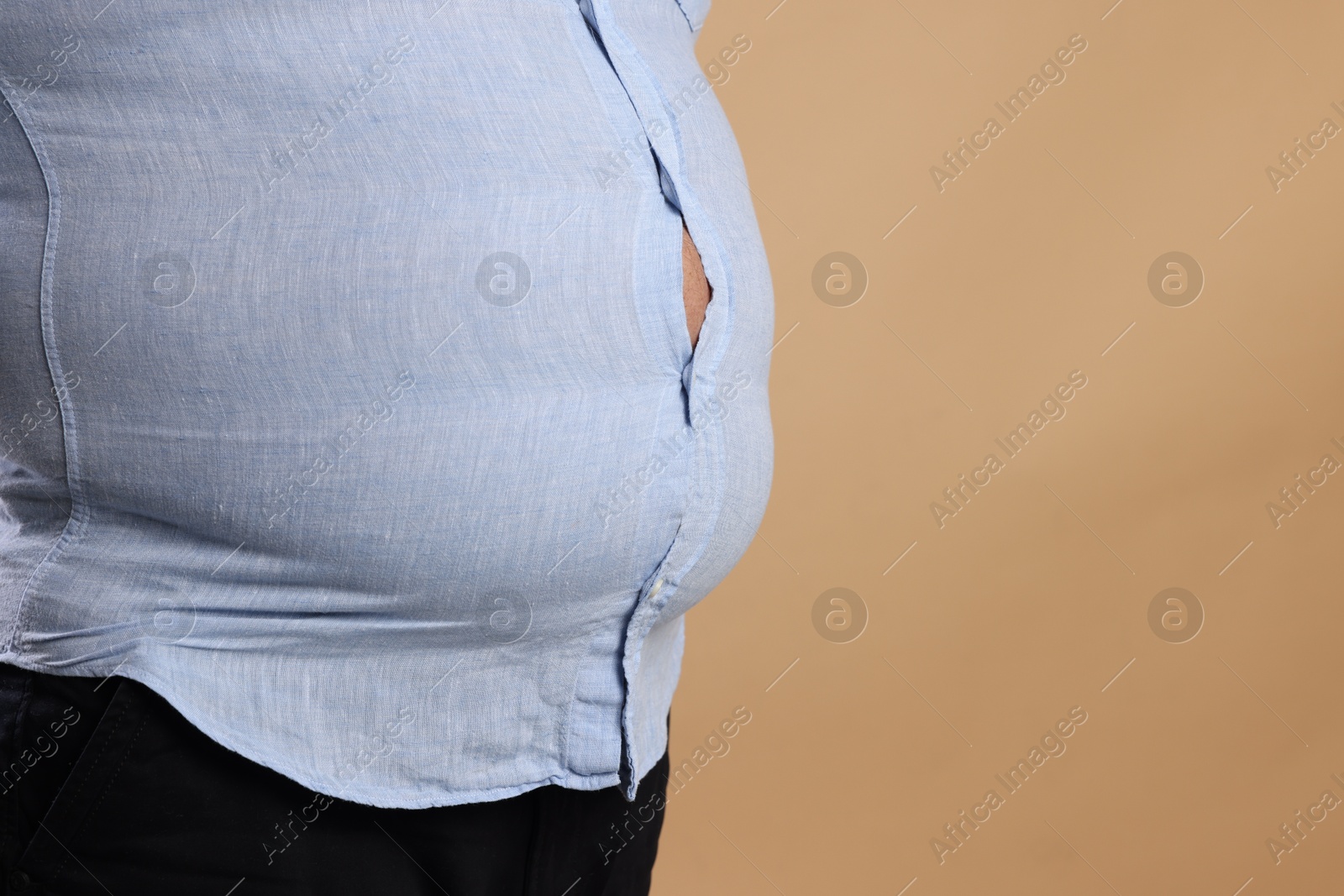 Photo of Overweight man in tight shirt on beige background, closeup. Space for text