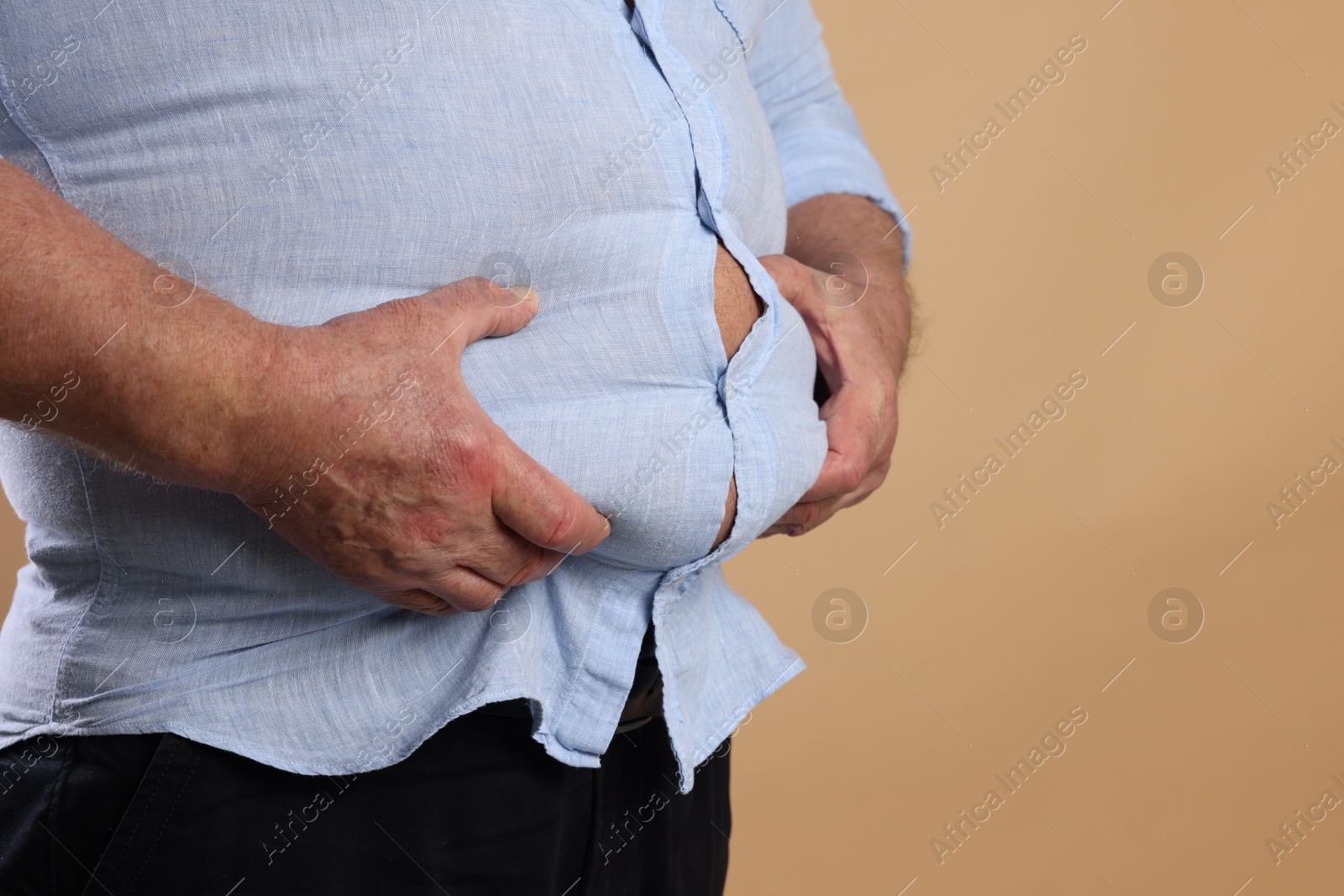 Photo of Overweight man in tight shirt on beige background, closeup. Space for text