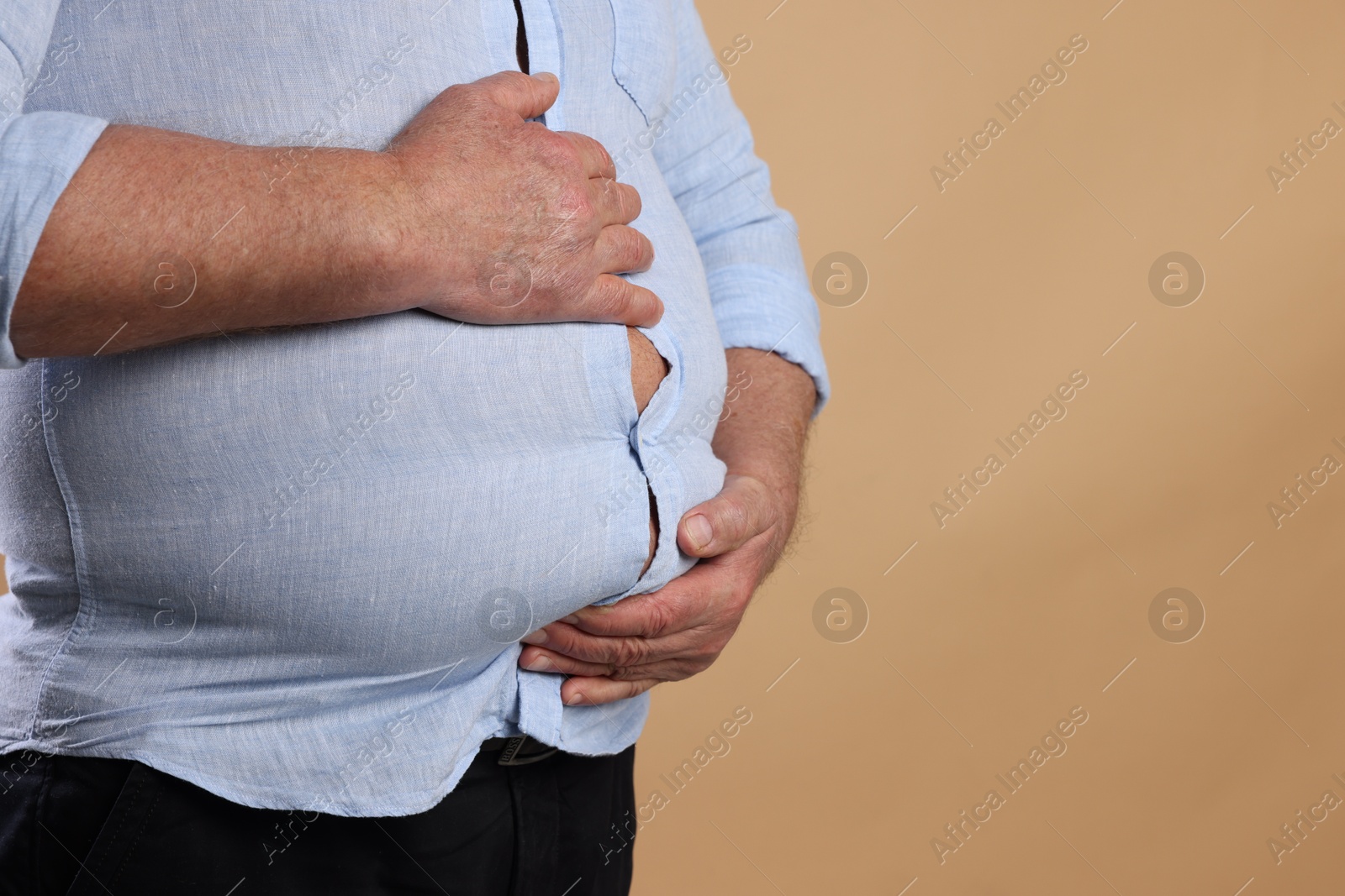 Photo of Overweight man in tight shirt on beige background, closeup. Space for text