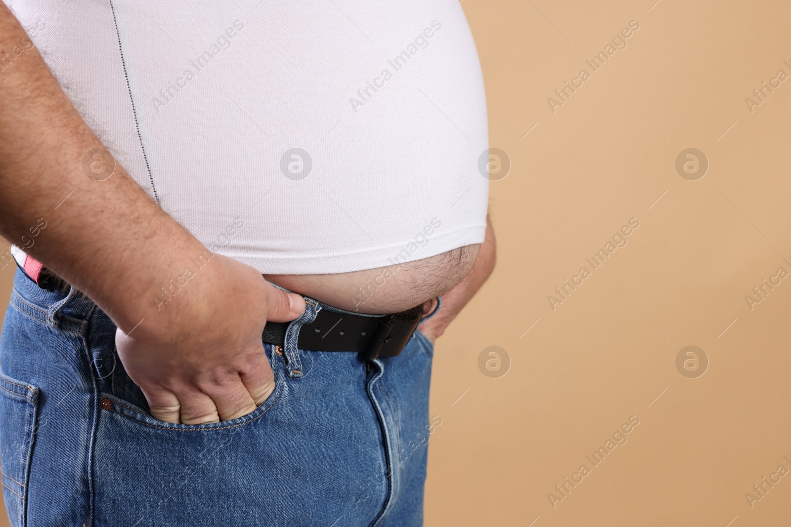 Photo of Overweight man in tight t-shirt on beige background, closeup. Space for text