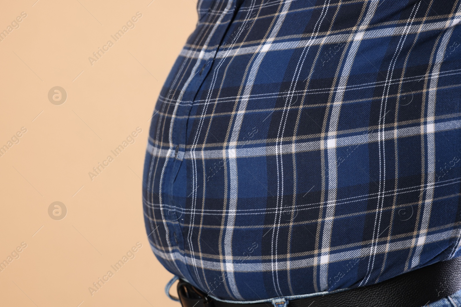 Photo of Overweight man in tight shirt on beige background, closeup. Space for text