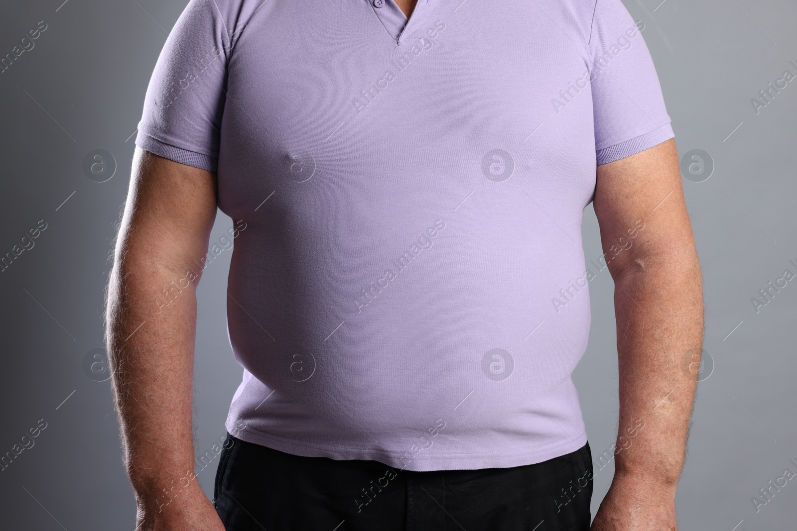 Photo of Overweight man in tight t-shirt on grey background, closeup