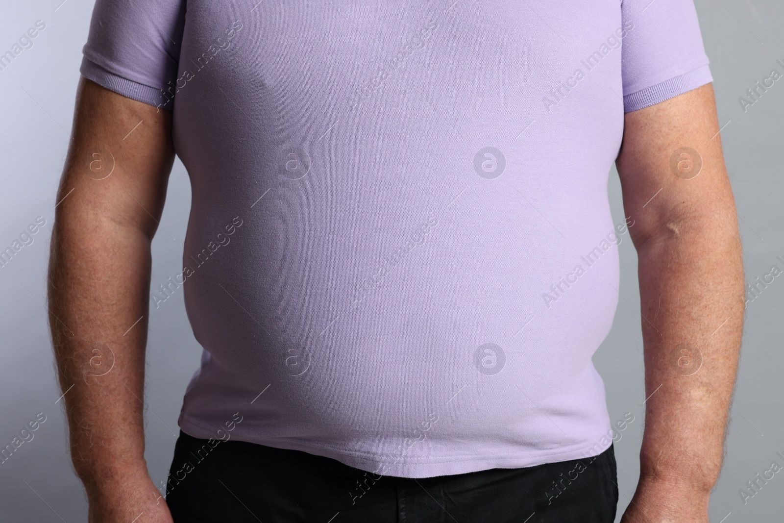 Photo of Overweight man in tight t-shirt on grey background, closeup