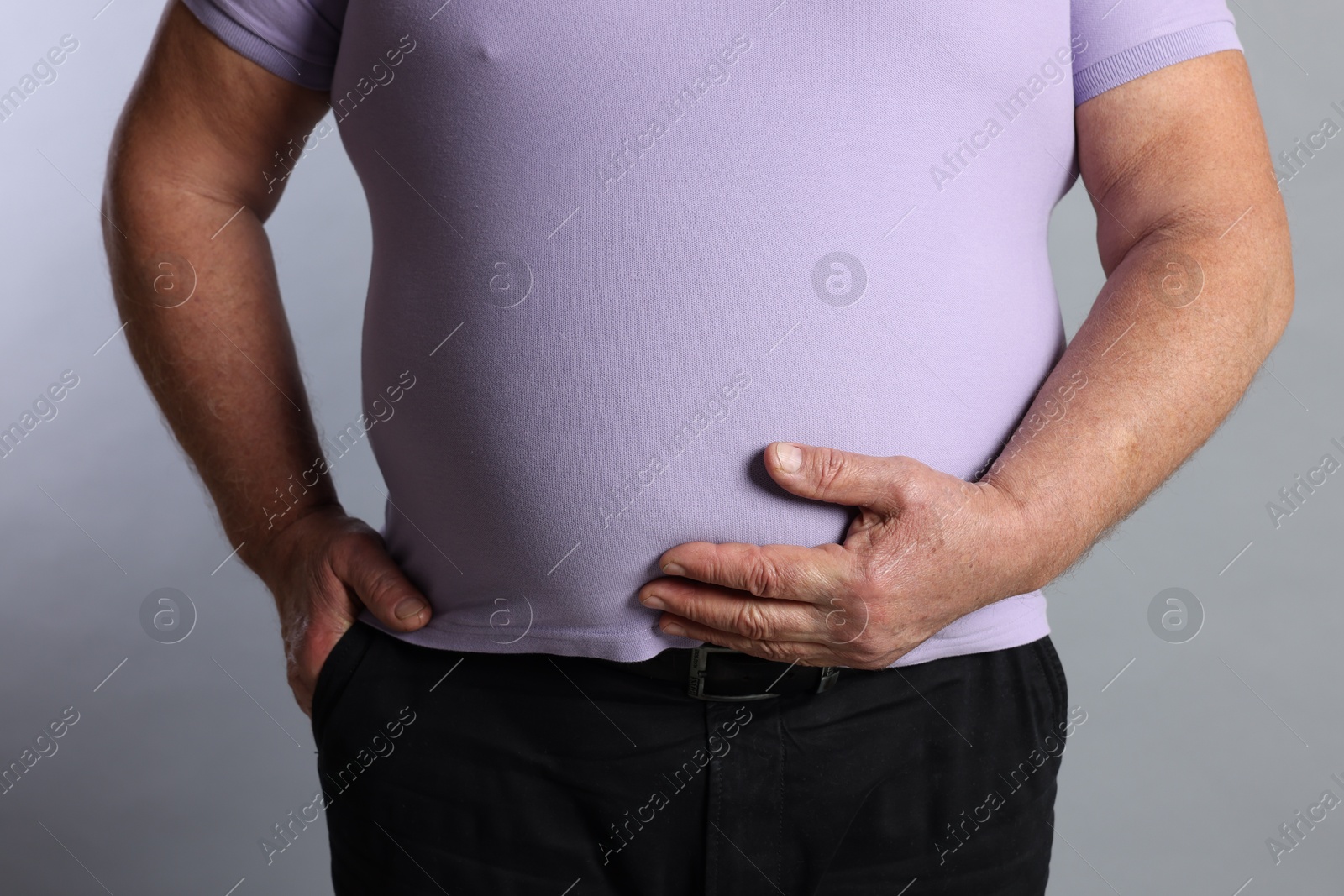 Photo of Overweight man in tight t-shirt on grey background, closeup