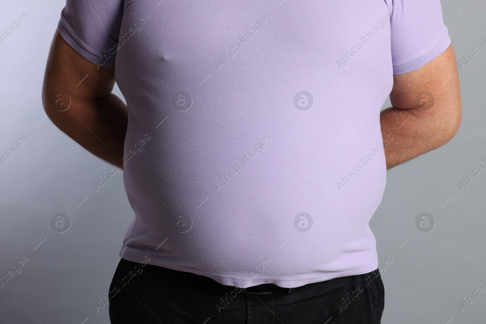 Photo of Overweight man in tight t-shirt on grey background, closeup