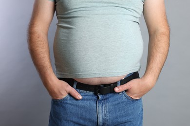 Photo of Overweight man in tight t-shirt on grey background, closeup