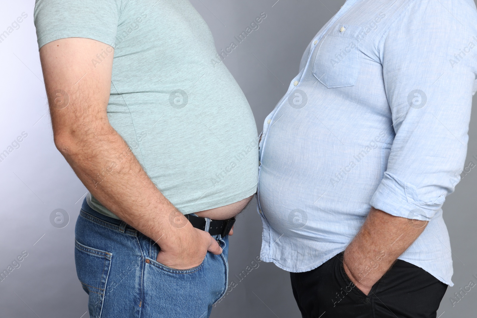 Photo of Overweight men in tight clothes on grey background, closeup