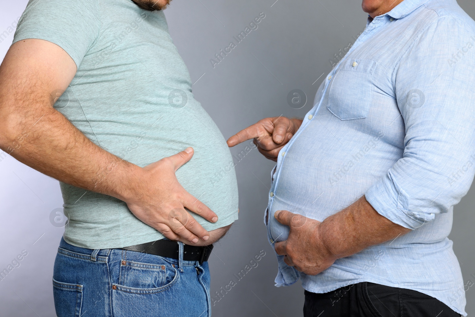 Photo of Overweight men in tight clothes on grey background, closeup