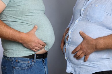 Photo of Overweight men in tight clothes on grey background, closeup