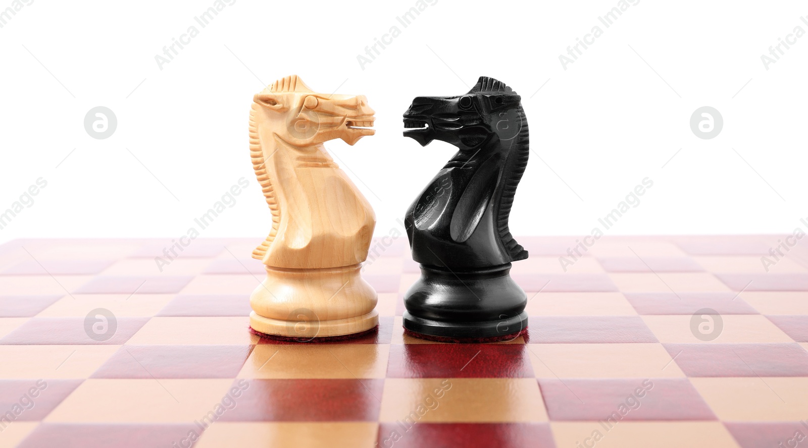 Photo of Black and white chess knights on checkerboard against white background. Competition concept