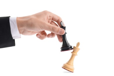 Photo of Man with black chess king knocking over white one on white background, closeup. Competition concept