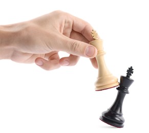 Photo of Man with white chess king knocking over black one on white background, closeup. Competition concept