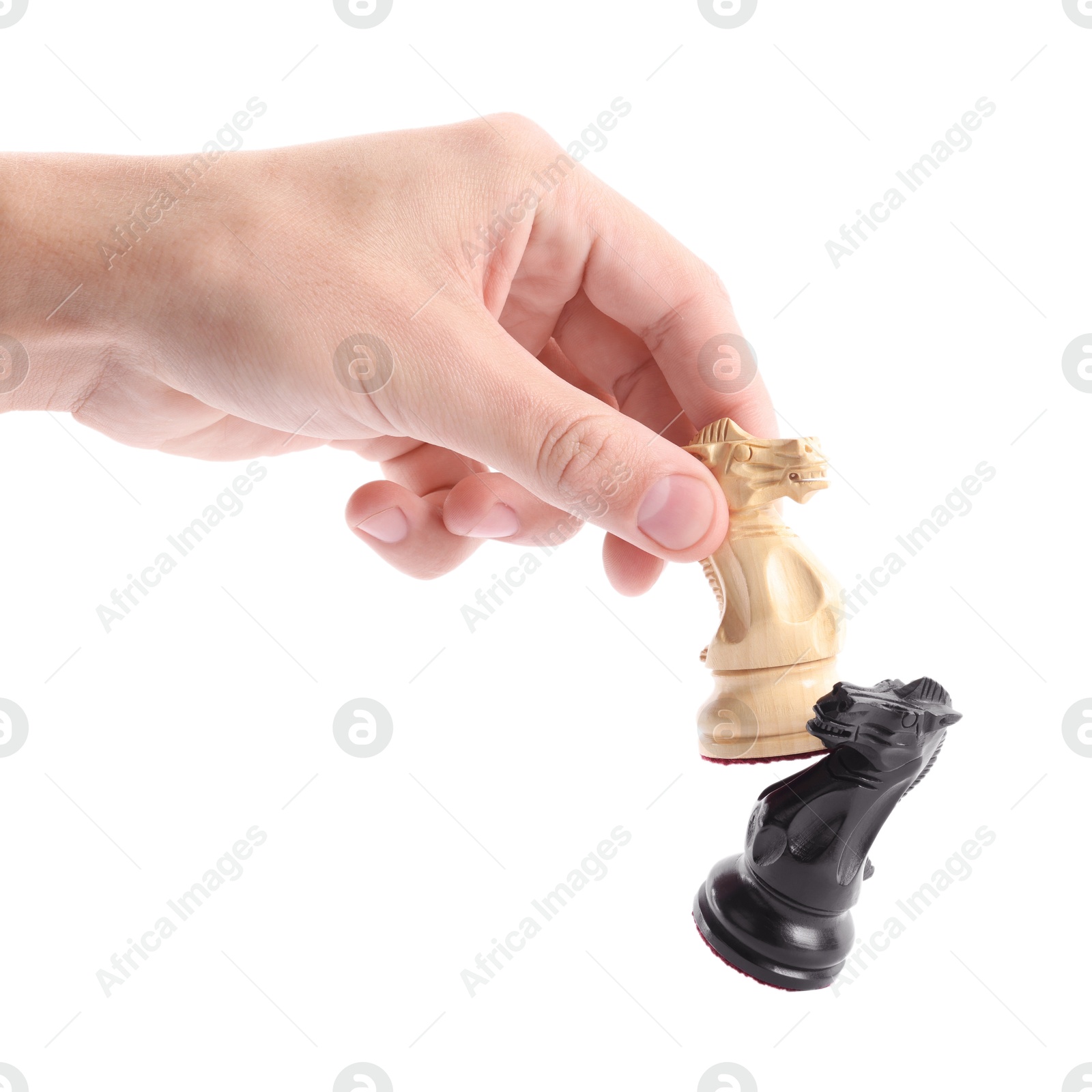 Photo of Man with white chess knight knocking over black one on white background, closeup. Competition concept