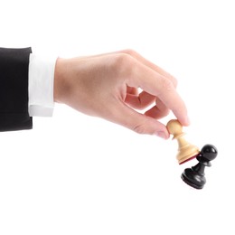 Photo of Man with white pawn knocking over black one on white background, closeup. Competition concept